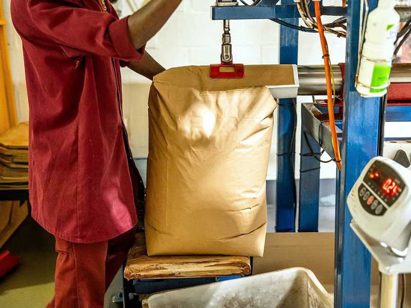 Sac en papier rempli de rooibos pasteurisé par un tube chez Carmién ; la balance est visible à droite
