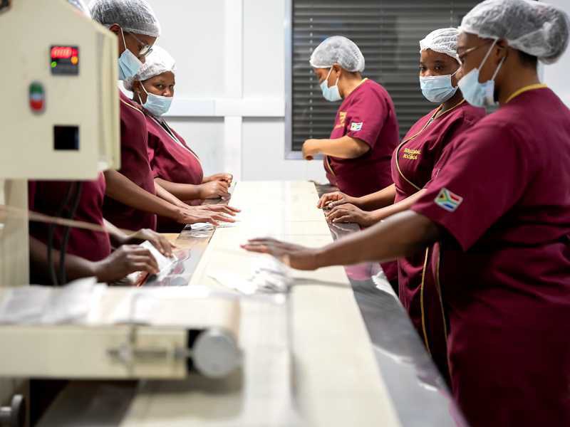Employée chez Carmién récupérant des sachets de thé fraîchement emballés à la sortie de la machine