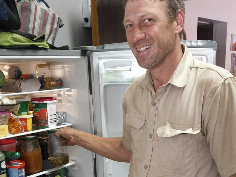 Une personne sort un verre d’infusion froide de Cancer Bush d’un réfrigérateur